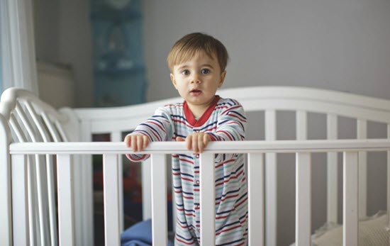 toddler standing in a big crib